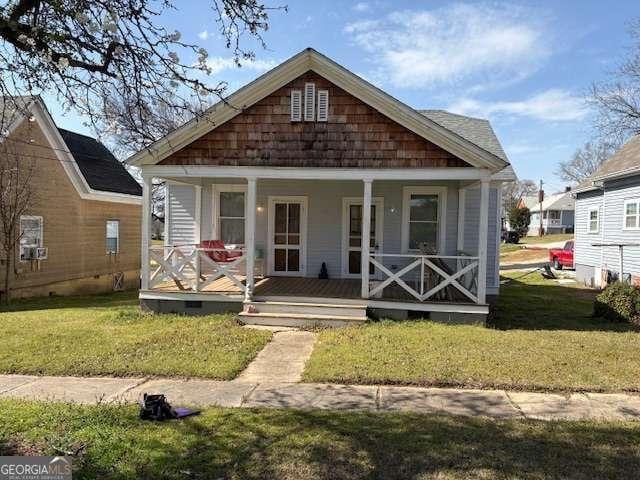 view of front of property featuring a porch, a front lawn, and crawl space