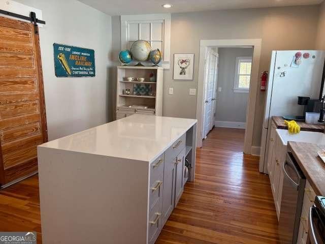kitchen with a barn door, wood finished floors, gray cabinets, and light countertops