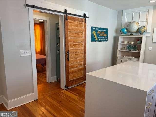interior space featuring light countertops, a barn door, and wood finished floors