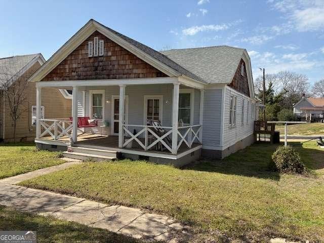 view of front of house featuring crawl space, a porch, a shingled roof, and a front lawn