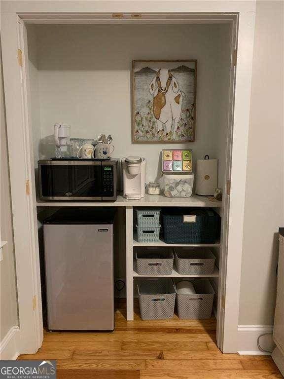 interior space featuring stainless steel microwave, fridge, and wood finished floors