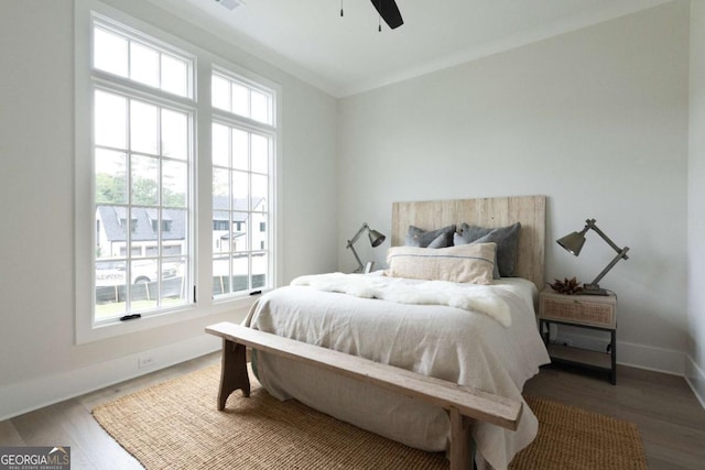 bedroom with a ceiling fan, crown molding, baseboards, and wood finished floors