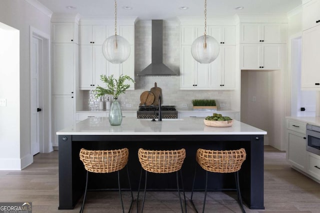 kitchen with white cabinetry, wall chimney range hood, and light wood-style floors