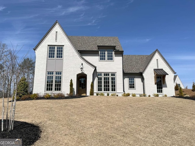 view of front of property featuring brick siding and roof with shingles