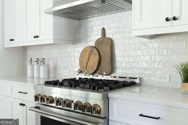 kitchen featuring range hood, decorative backsplash, stainless steel stove, white cabinets, and light countertops