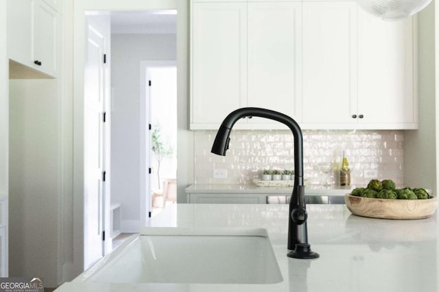 room details with backsplash, white cabinets, and a sink