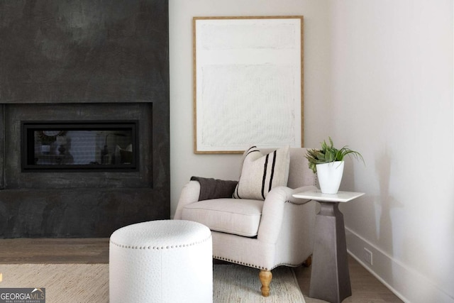 sitting room with a glass covered fireplace, baseboards, and wood finished floors