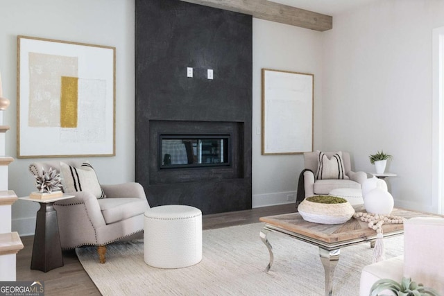 living room with baseboards, a large fireplace, beam ceiling, and wood finished floors