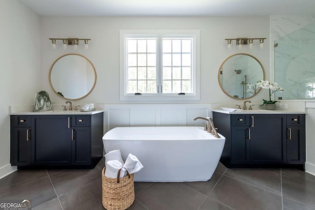 full bath with tile patterned floors, two vanities, a walk in shower, a sink, and a freestanding bath