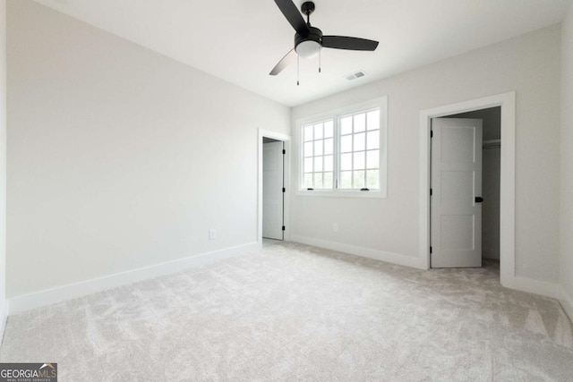 unfurnished bedroom featuring visible vents, carpet flooring, a walk in closet, and baseboards