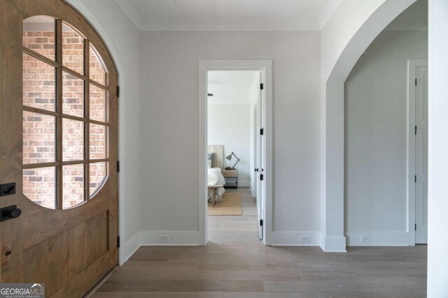 foyer with wood finished floors, baseboards, and arched walkways