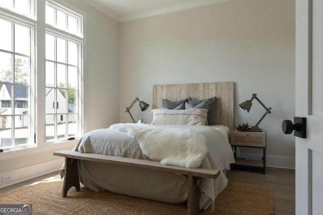 bedroom featuring baseboards, wood finished floors, and crown molding