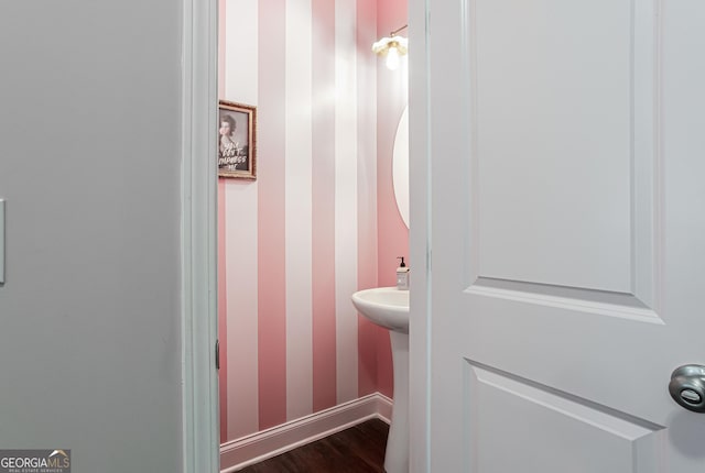 half bath with baseboards, wood finished floors, and wallpapered walls