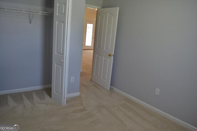 unfurnished bedroom with carpet flooring, baseboards, and a closet