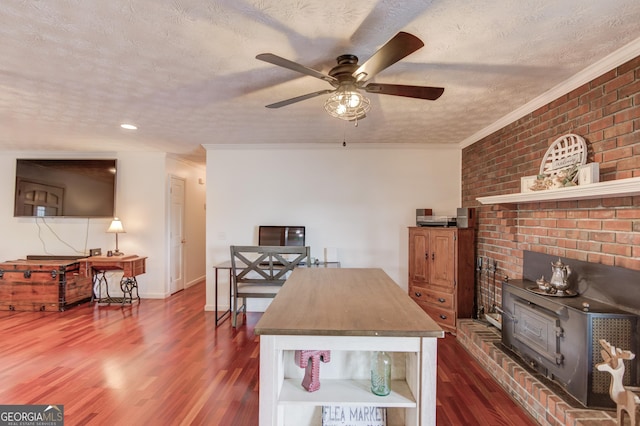 interior space with ornamental molding, a textured ceiling, dark wood-style floors, baseboards, and a wood stove