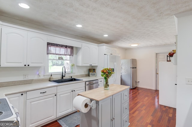 kitchen with a sink, stainless steel dishwasher, dark wood finished floors, freestanding refrigerator, and white cabinets