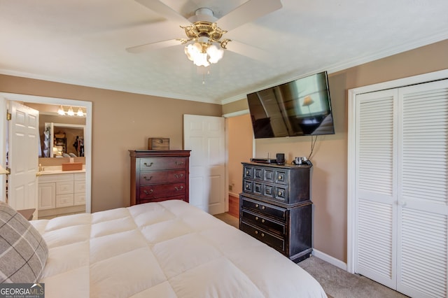 carpeted bedroom featuring ensuite bath, a closet, crown molding, baseboards, and ceiling fan