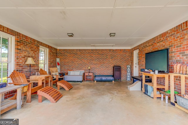 living area with concrete flooring and brick wall