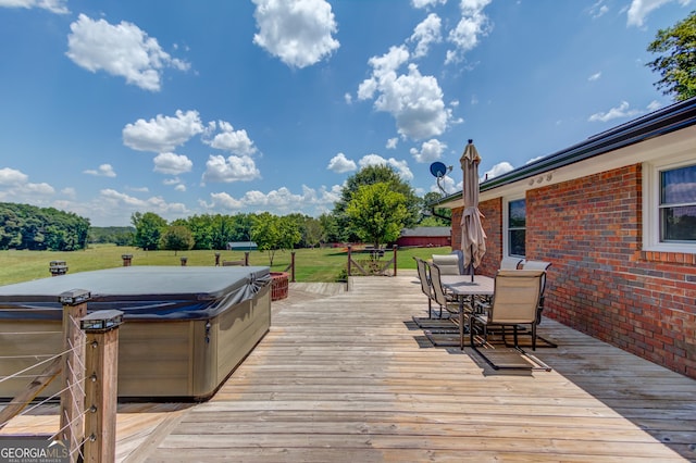 wooden terrace with outdoor dining space, a lawn, and a hot tub