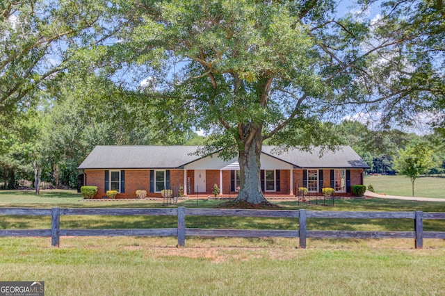 ranch-style house with a fenced front yard, brick siding, and a front lawn