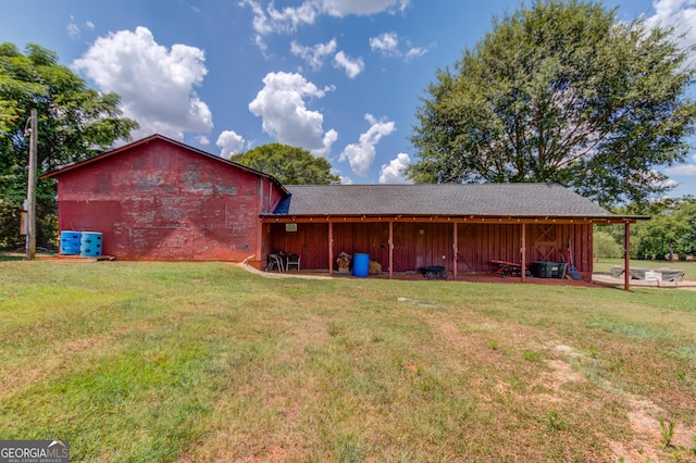 rear view of property with an outbuilding, a yard, and a pole building