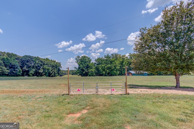 view of yard featuring a gate, a rural view, and fence