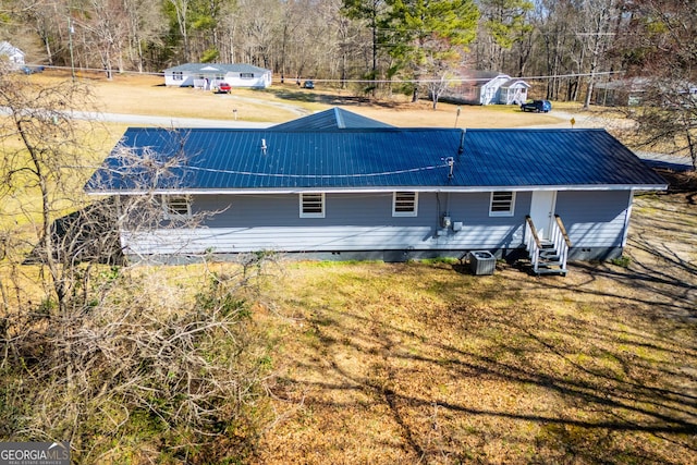 back of house featuring crawl space, a lawn, entry steps, and metal roof