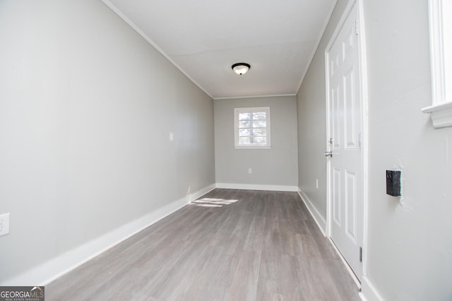 spare room featuring ornamental molding, baseboards, and wood finished floors