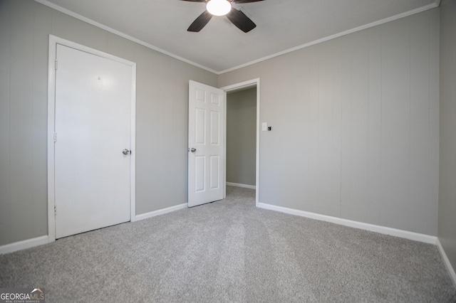 unfurnished bedroom with ceiling fan, baseboards, crown molding, and carpet