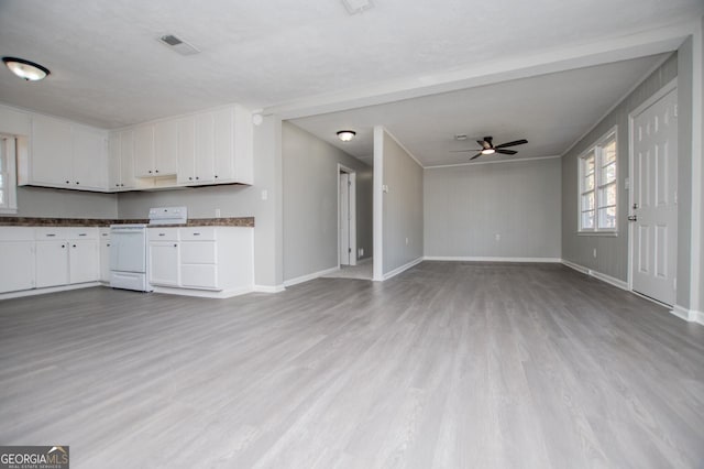 kitchen featuring dark countertops, light wood finished floors, visible vents, white stove, and white cabinetry