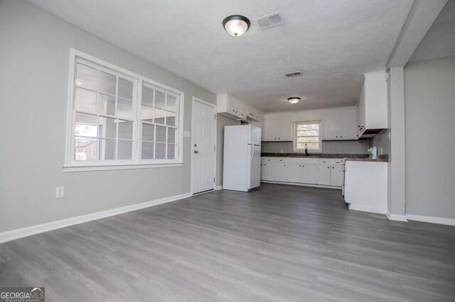 kitchen featuring visible vents, dark countertops, white cabinets, and freestanding refrigerator