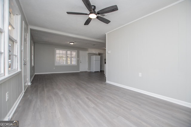 unfurnished living room featuring ceiling fan, baseboards, wood finished floors, and ornamental molding