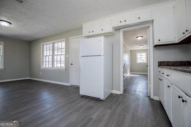 kitchen featuring dark countertops, white cabinets, dark wood-style flooring, and freestanding refrigerator