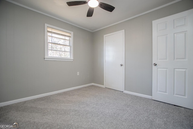 unfurnished bedroom with a ceiling fan, baseboards, carpet, and crown molding