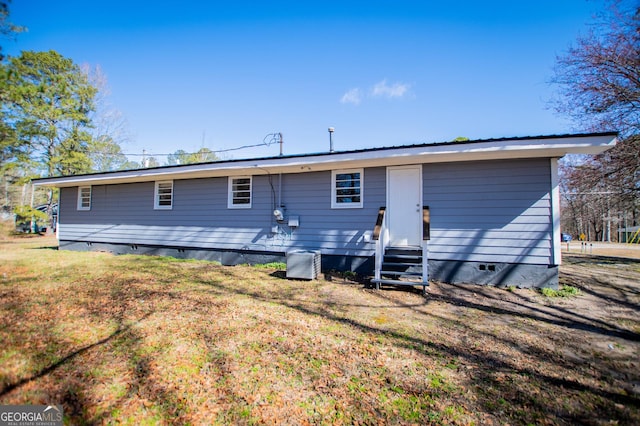 rear view of property with crawl space, a lawn, and entry steps