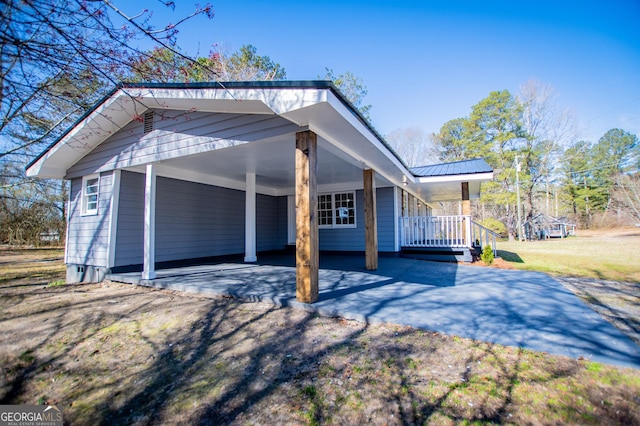 view of side of home featuring a carport, metal roof, a lawn, and aphalt driveway