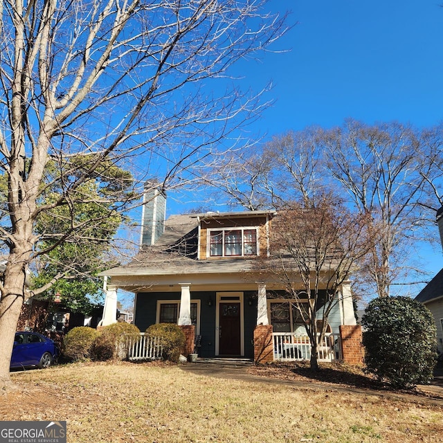 view of front of home featuring a front lawn, a porch, and a chimney