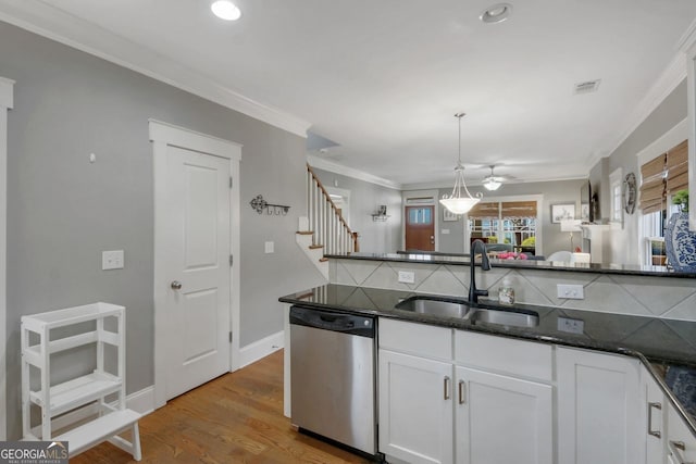 kitchen featuring dark stone countertops, a sink, white cabinets, dishwasher, and crown molding