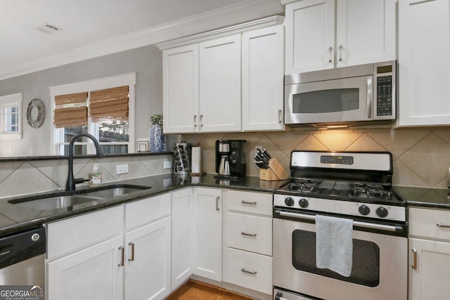 kitchen featuring a sink, decorative backsplash, stainless steel appliances, white cabinetry, and crown molding