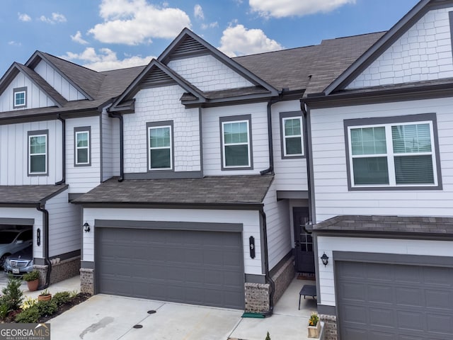 townhome / multi-family property with concrete driveway, an attached garage, board and batten siding, and a shingled roof