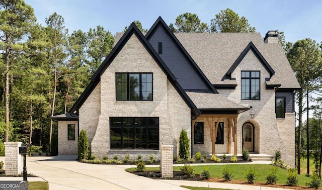 view of front of house featuring brick siding, a chimney, a front yard, and roof with shingles