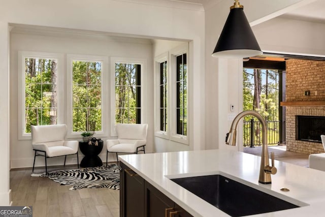 kitchen featuring open floor plan, a brick fireplace, light countertops, and a sink