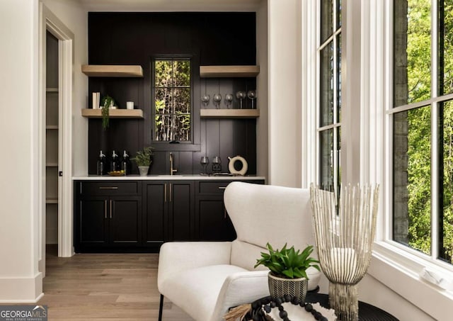 bar featuring a sink, wet bar, and light wood-style floors