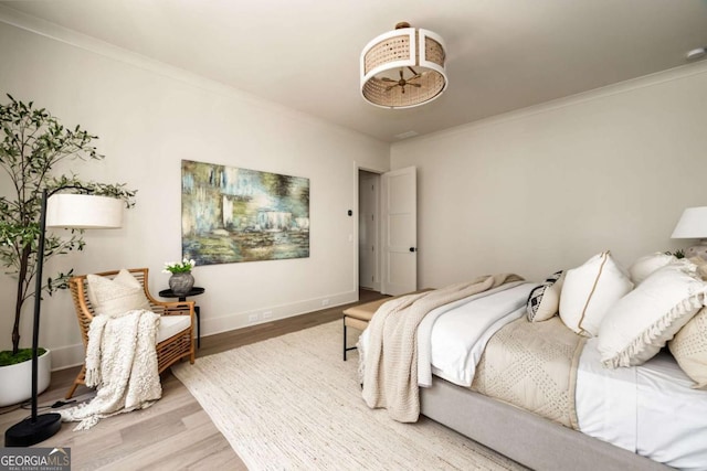 bedroom with baseboards, wood finished floors, and crown molding