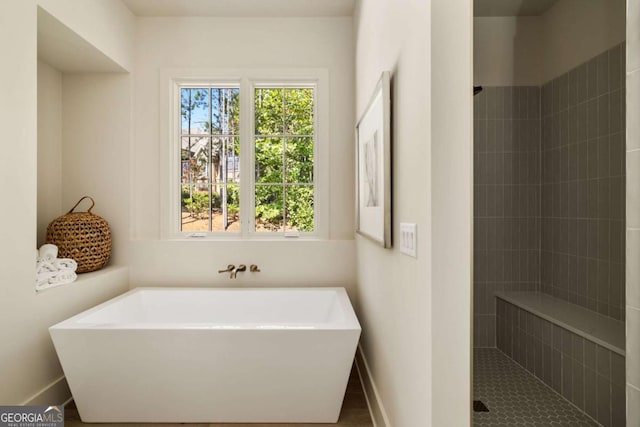 full bath with baseboards, a tile shower, and a freestanding bath