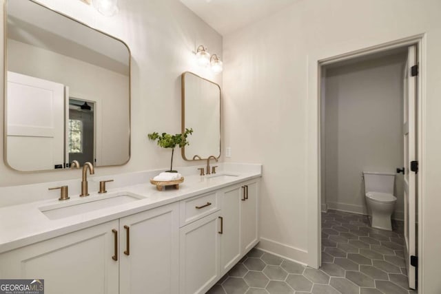 bathroom featuring tile patterned flooring, double vanity, toilet, and a sink