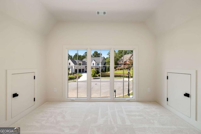 interior space featuring visible vents, carpet floors, and vaulted ceiling