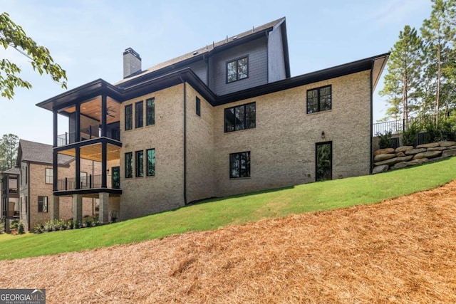 back of house with brick siding, a yard, a balcony, and a chimney