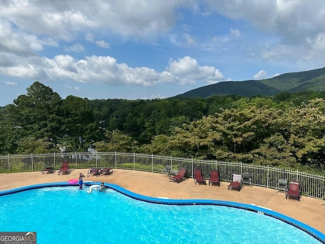 pool featuring a patio area, a mountain view, and fence