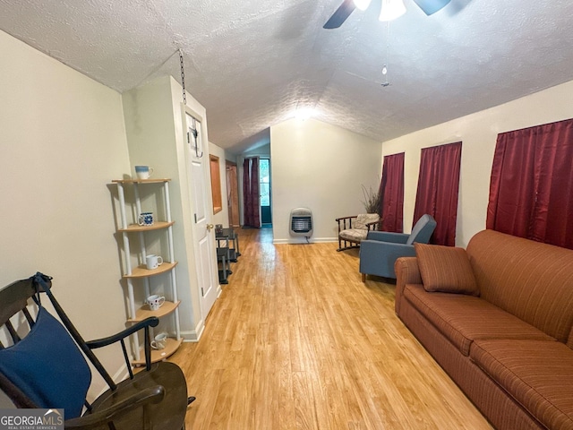 living area featuring a ceiling fan, wood finished floors, baseboards, lofted ceiling, and a textured ceiling